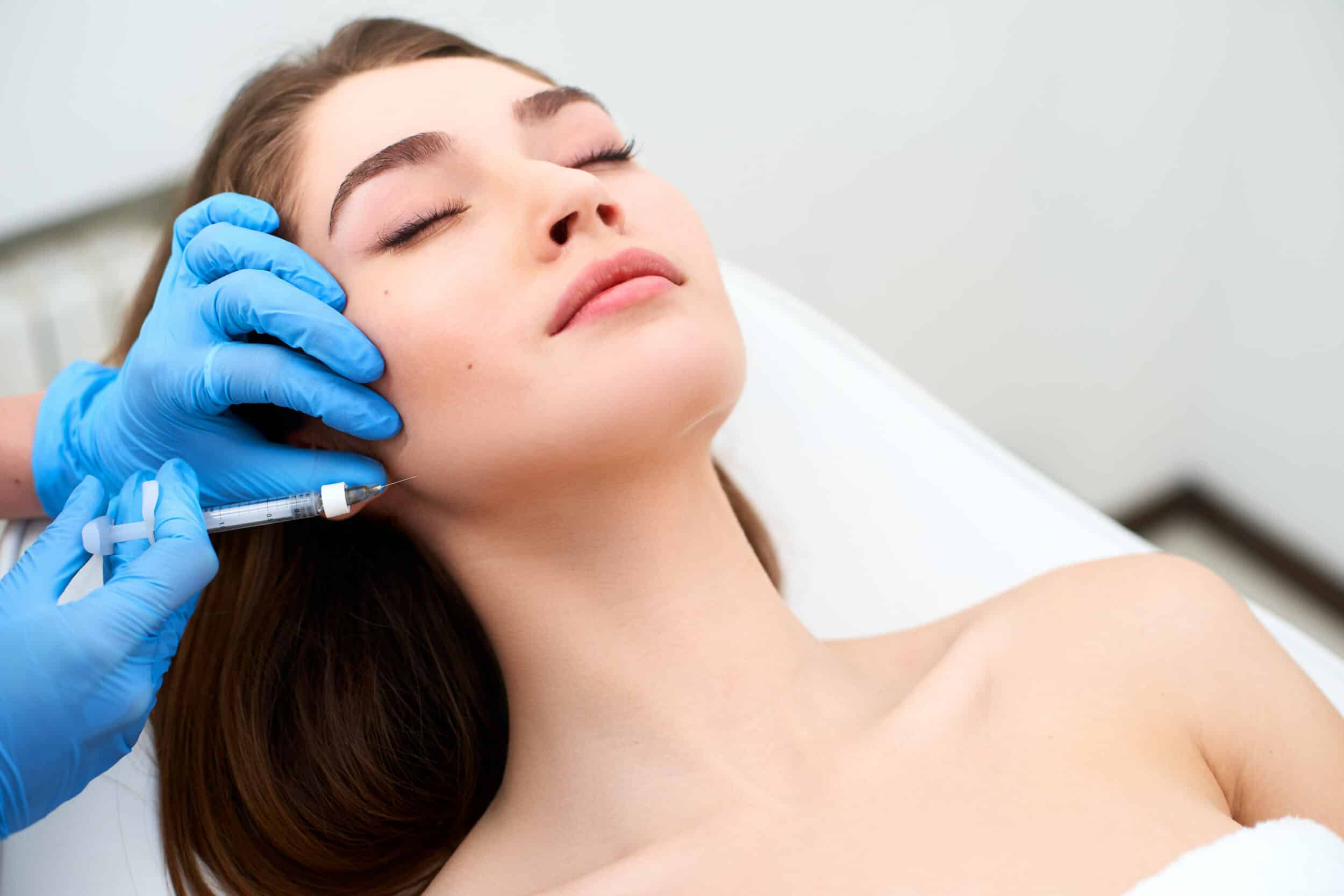 Woman getting Sculptra dermal filler injections in her jaw for a youthful contour
