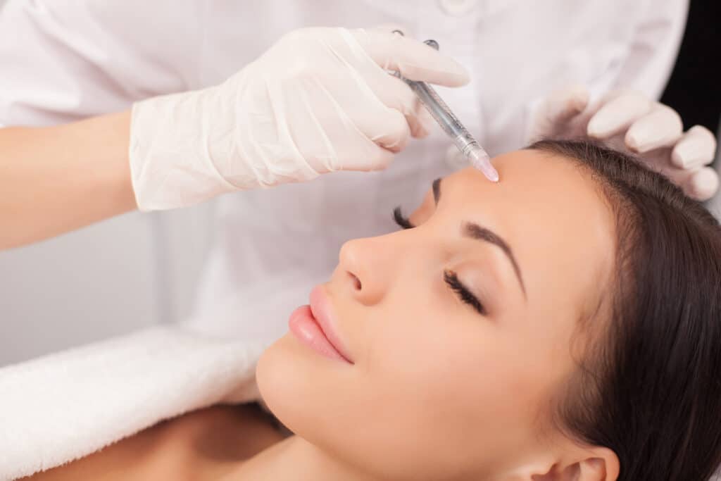 Doctor administers Botox® in woman's forehead as she gently smiles