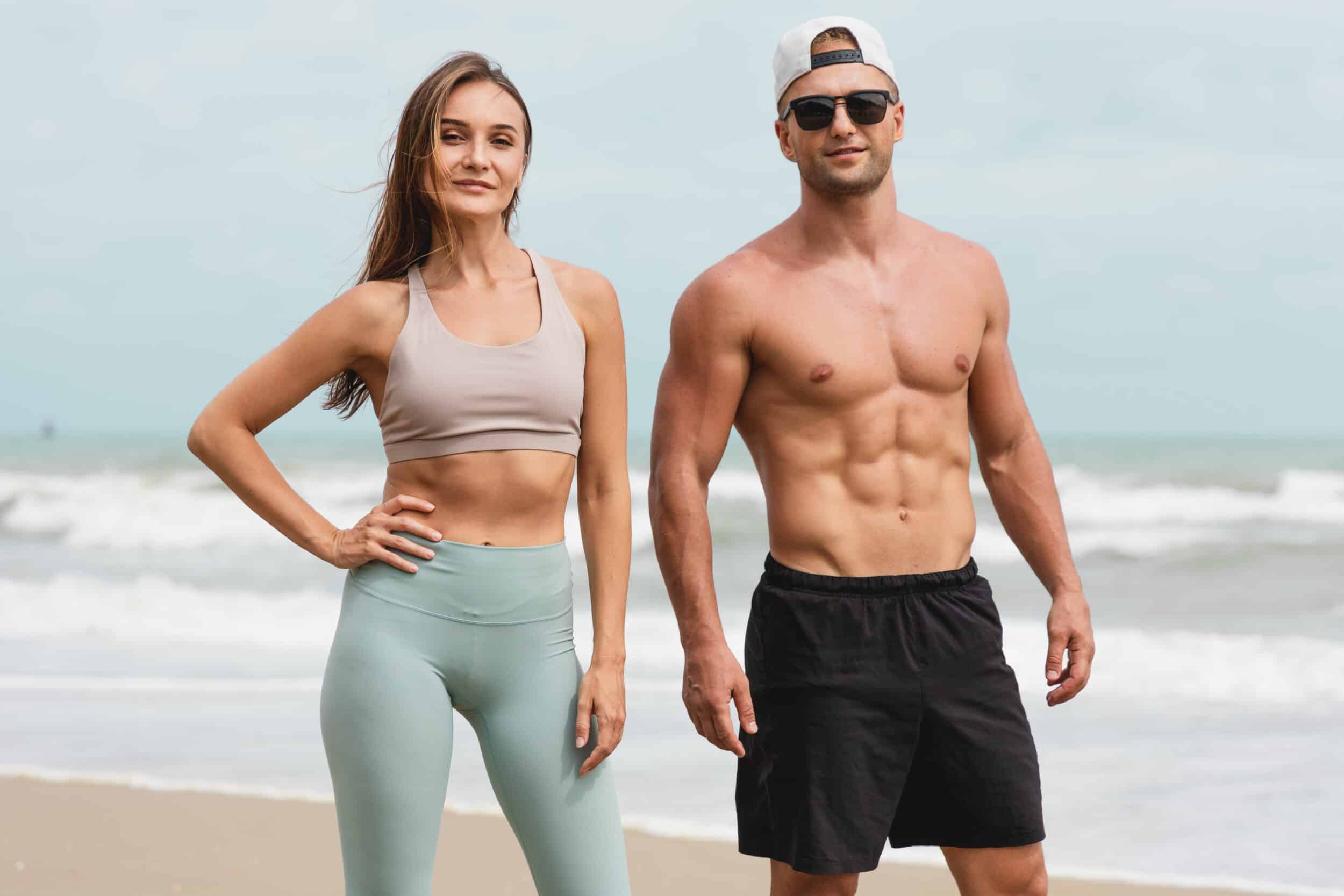 Fit and healthy couple on the beach, showing off their toned bodies after Emsculpt NEO treatments